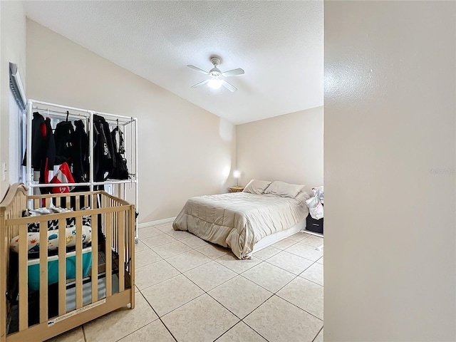 tiled bedroom with lofted ceiling, ceiling fan, and a textured ceiling