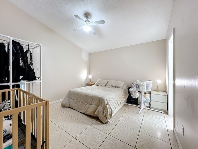 bedroom featuring ceiling fan, vaulted ceiling, a textured ceiling, and light tile patterned flooring