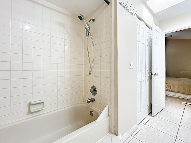 bathroom with tile patterned flooring, tiled shower / bath, and a skylight