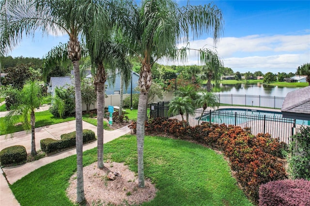 view of property's community with a yard, a pool, and a water view