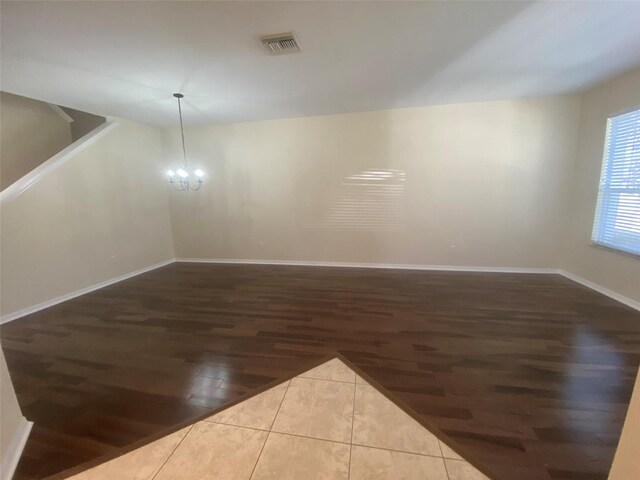 empty room with hardwood / wood-style floors and an inviting chandelier