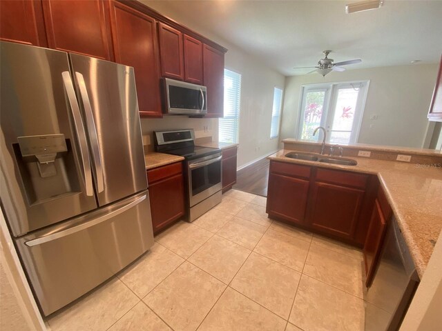 kitchen with light wood-type flooring, ceiling fan, sink, and appliances with stainless steel finishes