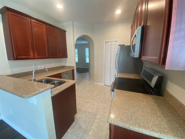 kitchen featuring light tile patterned floors, light stone countertops, stainless steel appliances, sink, and kitchen peninsula