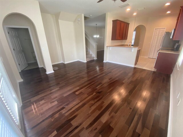 unfurnished living room with ceiling fan with notable chandelier, hardwood / wood-style floors, and sink