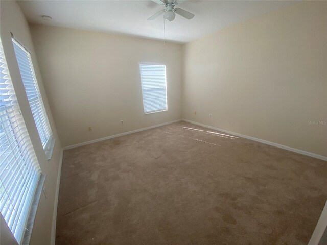 carpeted spare room with ceiling fan and plenty of natural light