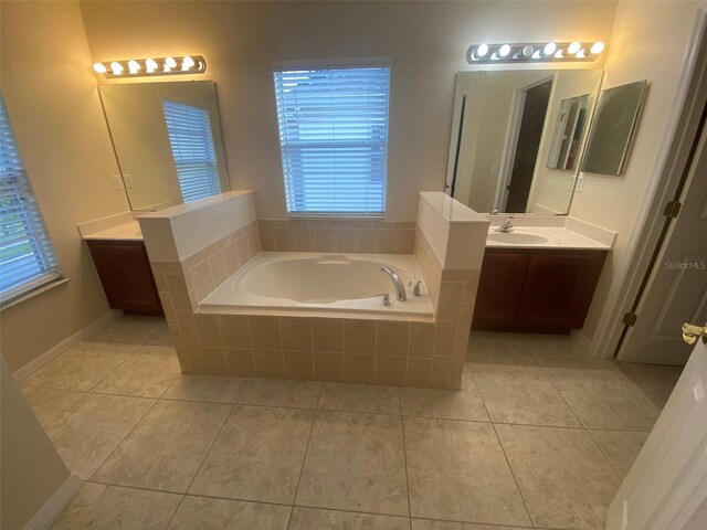 bathroom featuring vanity, a relaxing tiled tub, tile patterned floors, and a healthy amount of sunlight