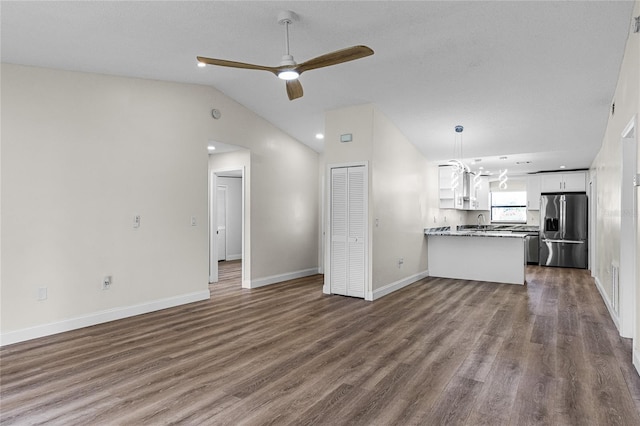 unfurnished living room featuring lofted ceiling, ceiling fan with notable chandelier, hardwood / wood-style flooring, and sink