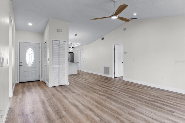 entryway featuring ceiling fan with notable chandelier, lofted ceiling, and light hardwood / wood-style flooring