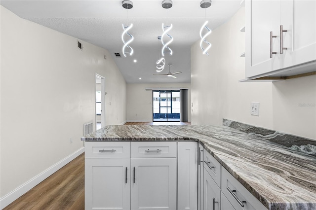 kitchen with white cabinets, hanging light fixtures, dark hardwood / wood-style floors, and kitchen peninsula