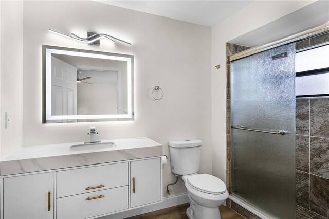 bathroom with vanity, hardwood / wood-style floors, walk in shower, toilet, and ceiling fan