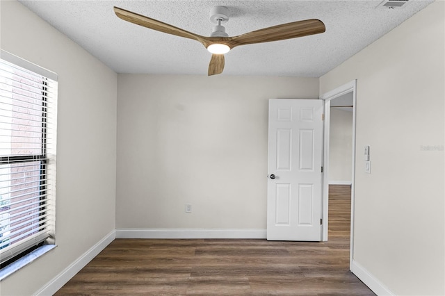 unfurnished room with dark wood-type flooring, ceiling fan, a textured ceiling, and a healthy amount of sunlight