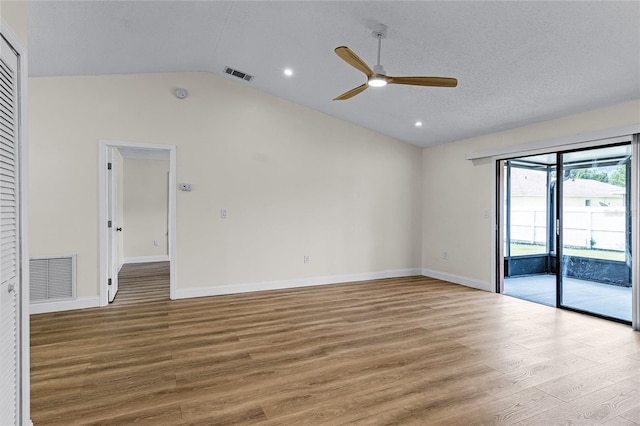 empty room with lofted ceiling, ceiling fan, a textured ceiling, and light hardwood / wood-style flooring