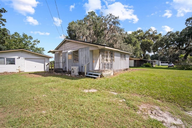 back of house with a garage, ac unit, an outbuilding, and a lawn