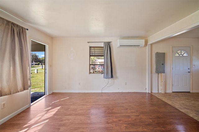 unfurnished room with a wealth of natural light, a wall mounted AC, hardwood / wood-style floors, and electric panel