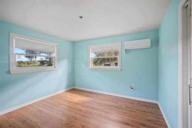 unfurnished room featuring hardwood / wood-style floors, plenty of natural light, and an AC wall unit