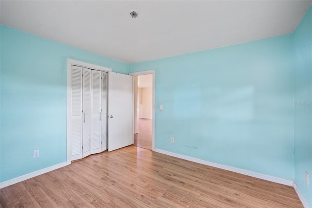 unfurnished bedroom with light wood-type flooring and a closet