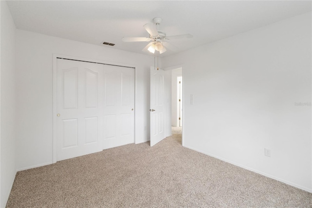 unfurnished bedroom featuring light carpet, baseboards, visible vents, ceiling fan, and a closet