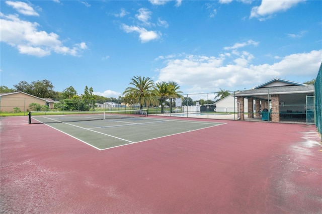 view of tennis court with community basketball court and fence