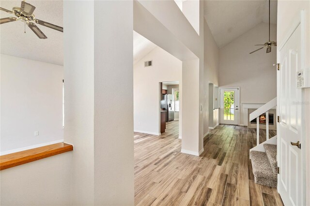 foyer entrance with ceiling fan, high vaulted ceiling, wood finished floors, and visible vents