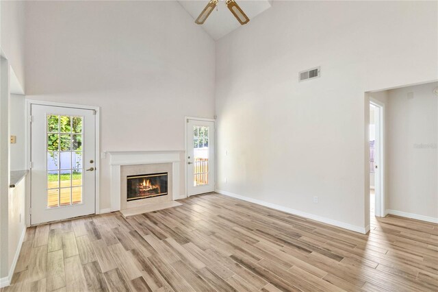 unfurnished living room featuring light wood-style flooring, plenty of natural light, a high end fireplace, and visible vents