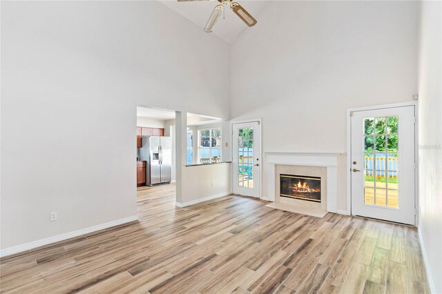 unfurnished living room with light wood-style floors, a fireplace, baseboards, and a wealth of natural light