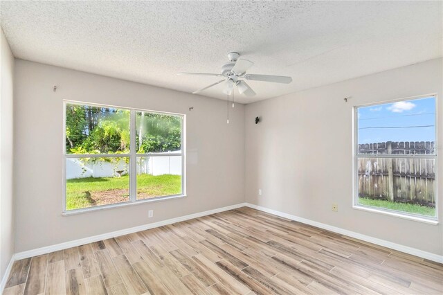 unfurnished room with light wood-style flooring, baseboards, and a textured ceiling