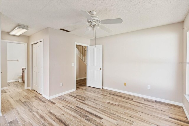 unfurnished room featuring a ceiling fan, baseboards, a textured ceiling, and light wood finished floors