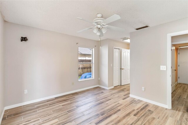 empty room featuring baseboards, visible vents, ceiling fan, a textured ceiling, and light wood-style floors