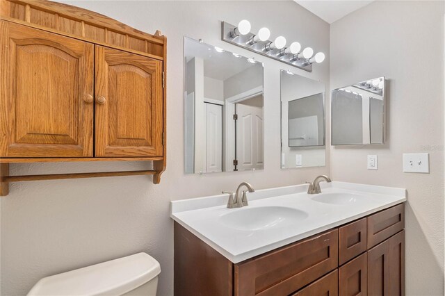 bathroom featuring a sink, toilet, and double vanity