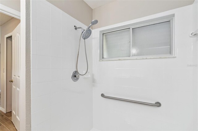 full bath featuring a tile shower and wood finished floors