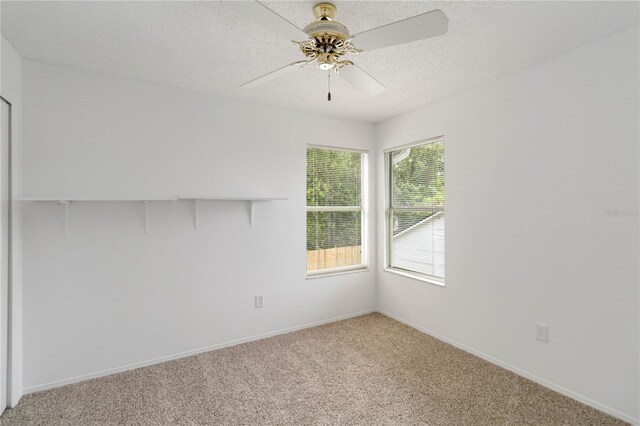 empty room featuring light carpet, ceiling fan, baseboards, and a textured ceiling