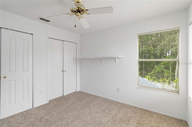 unfurnished bedroom with visible vents, baseboards, ceiling fan, carpet, and a textured ceiling