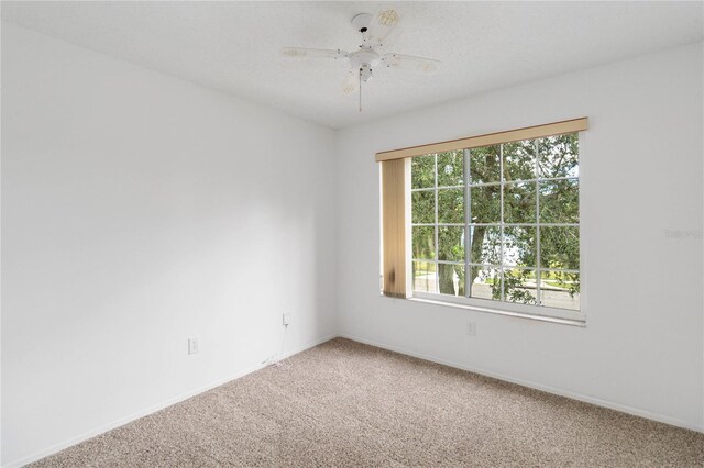 carpeted empty room with ceiling fan and baseboards