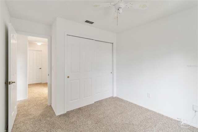 unfurnished bedroom with baseboards, visible vents, a ceiling fan, carpet flooring, and a closet