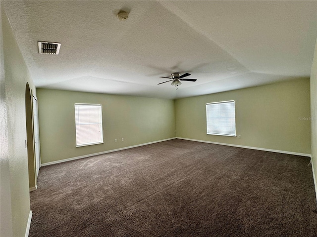 carpeted spare room with a textured ceiling, plenty of natural light, ceiling fan, and vaulted ceiling