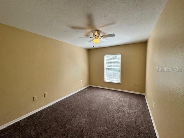 carpeted spare room with a textured ceiling and ceiling fan