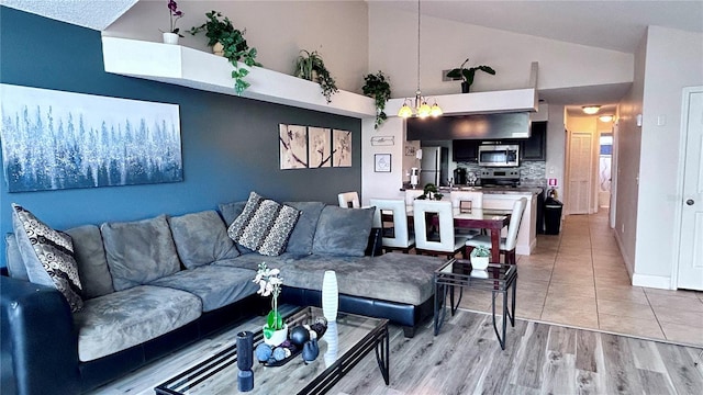 living room featuring high vaulted ceiling, light wood-type flooring, and a chandelier