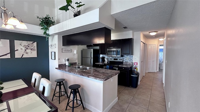 kitchen featuring light tile patterned floors, appliances with stainless steel finishes, kitchen peninsula, sink, and decorative backsplash