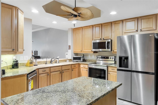 kitchen featuring light stone counters, stainless steel appliances, sink, kitchen peninsula, and ceiling fan