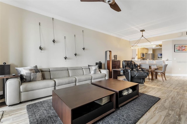 living room with ceiling fan, ornamental molding, and light wood-type flooring