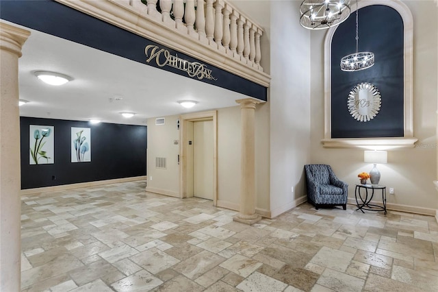 tiled entrance foyer featuring elevator, a chandelier, and decorative columns