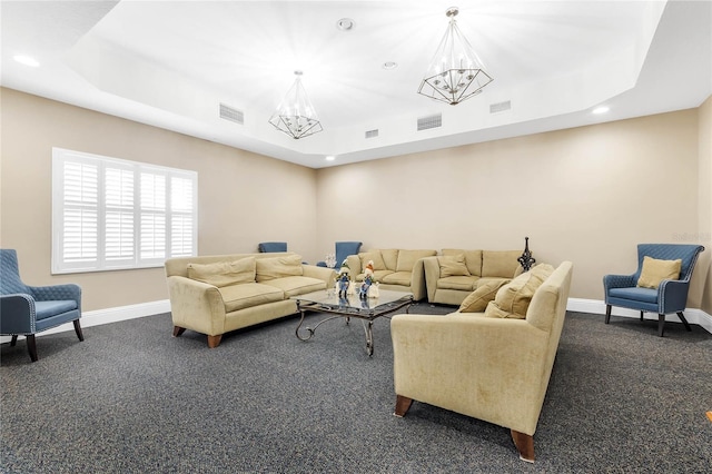 carpeted living room with a tray ceiling and an inviting chandelier