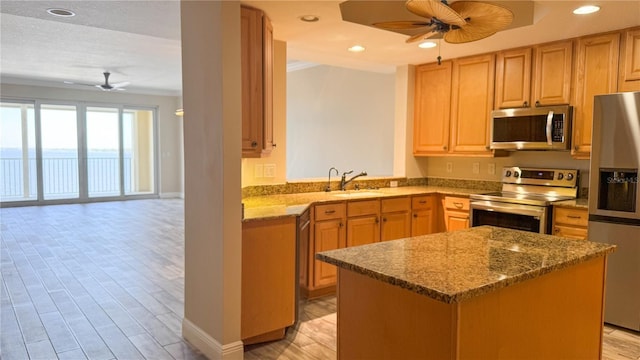 93 Delannoy Ave Unit 904, Cocoa, FL 32922 - kitchen featuring appliances with stainless steel finishes, ceiling fan, a sink, open floor plan, and dark stone counters