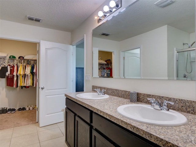 bathroom featuring tile patterned flooring, a shower with door, a textured ceiling, and vanity