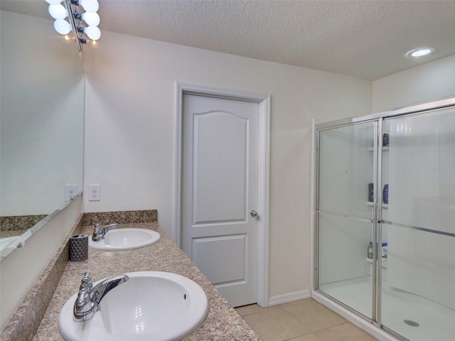 bathroom featuring vanity, a textured ceiling, tile patterned floors, and a shower with door