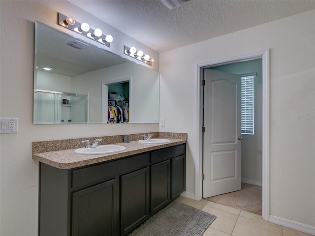 bathroom with a textured ceiling, vanity, an enclosed shower, and tile patterned floors