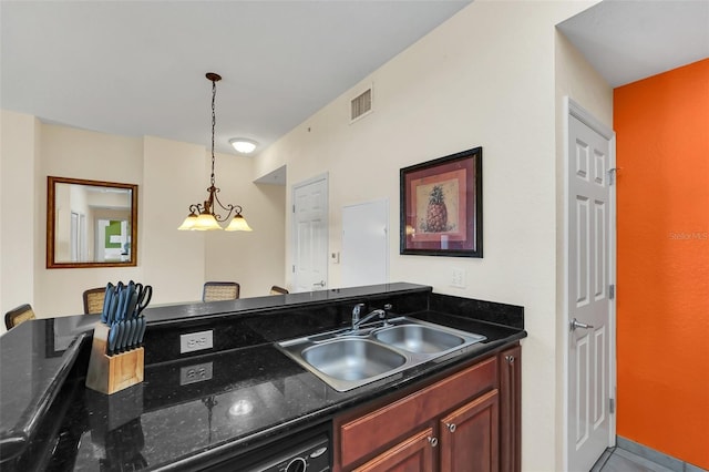 kitchen featuring visible vents, a sink, dark stone counters, dishwasher, and hanging light fixtures