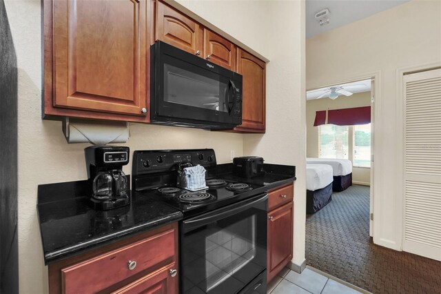 kitchen with dark stone counters, ceiling fan, light tile patterned floors, and black appliances