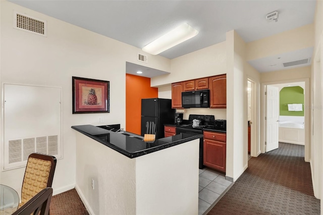 kitchen featuring visible vents, dark countertops, black appliances, and a peninsula