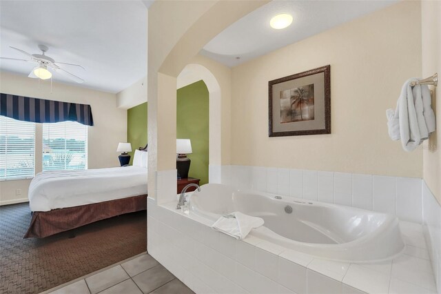 bathroom with tile patterned flooring, a relaxing tiled tub, and ceiling fan